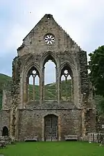 Photographie d'un pignon d'église en ruines, en core debout et percé de lancettes et d'une rosace.