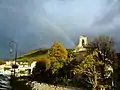 Vue d'un arc-en-ciel et du clocher du temple réformé sur la commune de Valleraugue.