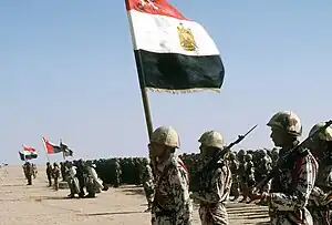 Soldats en uniforme dans le désert portant un drapeau égyptien