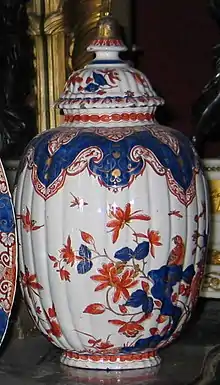 Un vase en porcelaine blanche décoré de fleurs bleues et rouges.