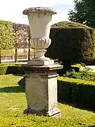 Grande vasque sur un piédestal située dans un parterre près du bassin.