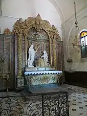 Retable en bois polychrome. Deux statues, dont une du Christ, encadrent un Sacré Cœur. En bas, un aigle doré (référence à Bossuet)