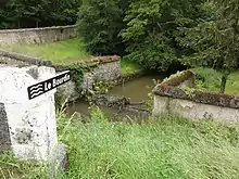 Photographie en couleurs d'un petit cours d'eau vu depuis un pont.