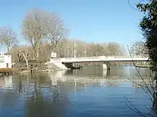 Photographie en couleurs d'une rivière avec un pont en arrière-plan.