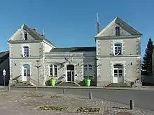 Photographie en couleurs d'un bâtiment composé d'une aile centrale prolongée de part et d'autre par deux pavillons plus hauts.