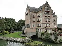 Photographie en couleurs d'un bâtiment à plusieurs étages établi au-dessus d'un cours d'eau.