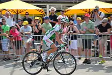 Photographie d'un coureur cycliste, habillé en vert en blanc, vu de profil.