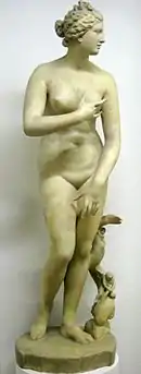 Statue antique, en marbre. Femme nue, tête tournée à gauche, bras fléchis, un dauphin le long de sa jambe gauche