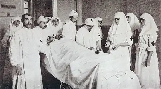 Photo en noir et blanc d'un groupe de personnel hospitalier autour de la table d'opération où est couché un patient.