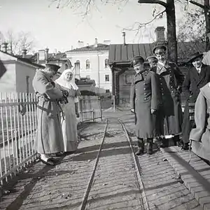 Photo en noir et blanc de six personnes en extérieur, de part et d'autre d'une voix ferrée.