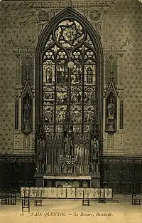 Photographie en noir et blanc. Au premier plan, un autel. En arrière-plan, une grande verrière.