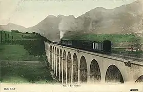 Carte postale en couleur du représentant le viaduc ferroviaire dans une vue à niveau, avec un train à vapeur le traversant, vers le tournant du XXe siècle..