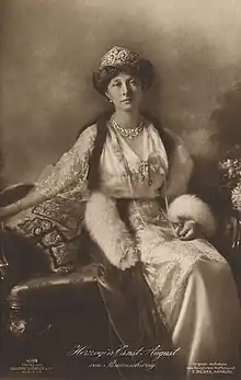 Photographie en noir et blanc d'une femme assise portant une tenue de fête et des bijoux