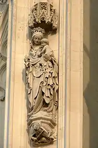 Statue de la Vierge à l'Enfant. À ses pieds, un homme joue du rebec, sorte de violon à trois cordes