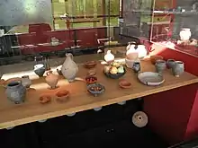 Photographie d'un assortiment de vaisselle romaine en terre cuite et céramique sur une table.