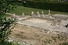 Photographie des vestiges d'un habitat antique avec des bases de colonnes entourant une cour.