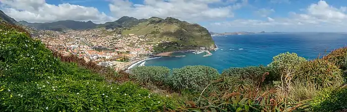 Une ville dans le creux d'une baie. Quelques éléments portuaires. Quelques éléments montagneux.