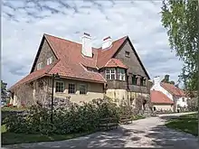 Maison vue de trois-quart, façade jaune pâle, tuiles rouges.