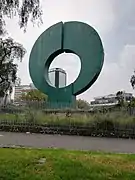 Dans la pelouse, une grande sculpture d'un disque vert troué au milieu.