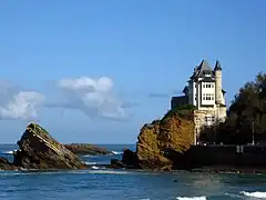 Vue d'une villa perchée sur un rocher surplombant la mer.
