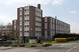 vue d'un bâtiment et d'une tour accolés, bruns et blancs.