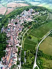 Vue aérienne d'un village à l'habitat s'étalant entre des massifs boisés et des cultures