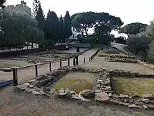 vue des ruines de 2 rangées de maisons hautes de 2 niveaux de pierres sombres