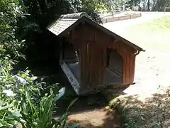 Photographie en couleurs d'un lavoir en bois au bord d'une rivière.