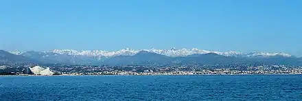 La mer Méditerranée au premier plan et les montagnes enneigées du massif dans le lointain.