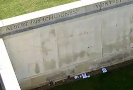 Des coquelicots de papier sont fixés au mur, des fleurs et des plaques sont déposées à sa base (vue du haut de la tour).