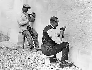 Deux hommes en train de graver des noms sur une face du Monument commémoratif du Canada à Vimy.