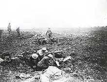 Photo en noir et blanc de militaires dans des cratères d'obus avec des mitrailleuses et des munitions