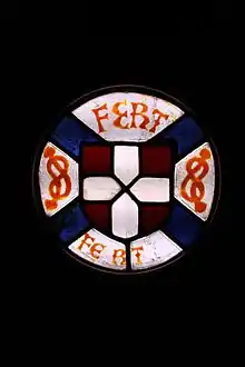 Vitrail représentant les symboles de la maison de Savoie, le blason de rouge à la croix d'argent, ainsi que des nœuds ou lacs d'Amour et le devise FERT.