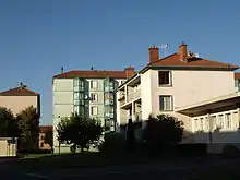 Photographie de logement HLM : au premier plan, un immeuble de trois étages rose clair et derrière, un immeuble de cinq étages vert pâle.