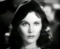 Image un peu floue, en noir et blanc, du visage sérieux d'une femme portant un béret sombre.