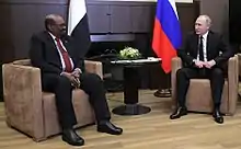 Rencontre entre deux chefs d'État en costume assis face à face dans des fauteuils