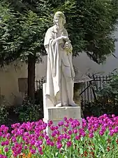 Statue de Voltaire entourée de fleurs.