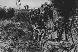 Pendant la Grande Guerre, près de Chaulnes, des soldats français en poste avancé, protégés derrière un mur, attendent l'ennemi tout proche.