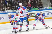 Trois joueurs de hockey sur glace en uniforme blanc, bleu et rouge