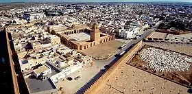 Photographie montrant une vue aérienne de la Grande Mosquée de Kairouan. Celle-ci est située à l'extrémité nord-est de la médina, à proximité des remparts dont elle n'est séparée que par une esplanade.
