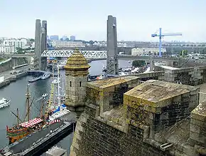 Vue sur une fortification, avec un pont visible au loin.