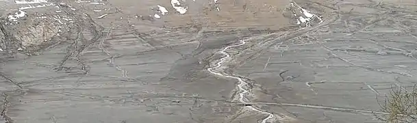 Vue de la route avec un petit pont et des traces d'habitations.