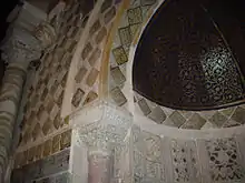 Vue partielle de la partie supérieure du mihrab, montrant la demi-coupole peinte, réalisée en bois cintré, de la niche, ainsi que les carreaux lustrés ornant l'intérieur et l'encadrement de celle-ci.