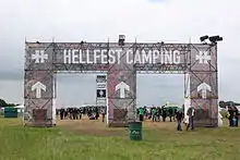 Le portique d'entrée du camping avec des festivaliers se dirigeant vers les scènes.
