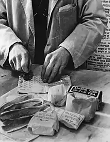 Rationnement des civils :Un commerçant britannique oblitère des tickets de rationnement en avril 1943.