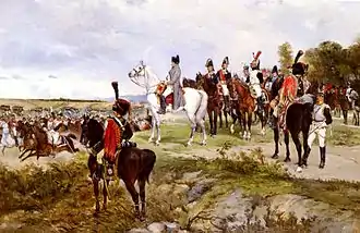 Napoléon, à cheval sur un promontoire et entouré de ses officiers, regarde passer des cavaliers qui brandissent leur sabre pour le saluer.