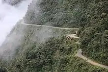 Photographie d'une route étroite qui serpente à flanc de montagne dans une végétation luxuriante.