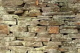 Parement d'un mur réalisé en pierres plates posées dans le sens du lit de carrière et avec croisement des joints (lieu non précisé).