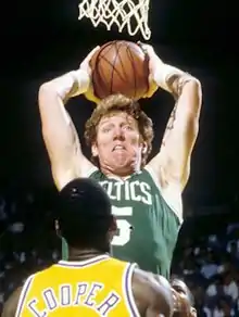 Un joueur des Celtics ballon en main prêt à marquer face à un joueur en jaune vu de dos