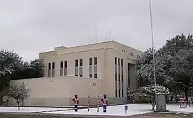 Vue d'un bâtiment de plusieurs étages. De la neige est présente sur les trottoirs.